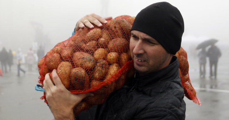 Мужчина несет мешок картофеля с продуктовой ярмарки в Ставрополе.