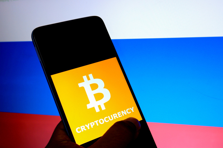 Приложение для работы с криптовалютами на фоне российского флага. Фото: Avishek Das/ Keystone Press Agency/ Global Look Press