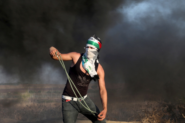 Палестинец кидает камни в израильских полицейских. 14 октября 2015.