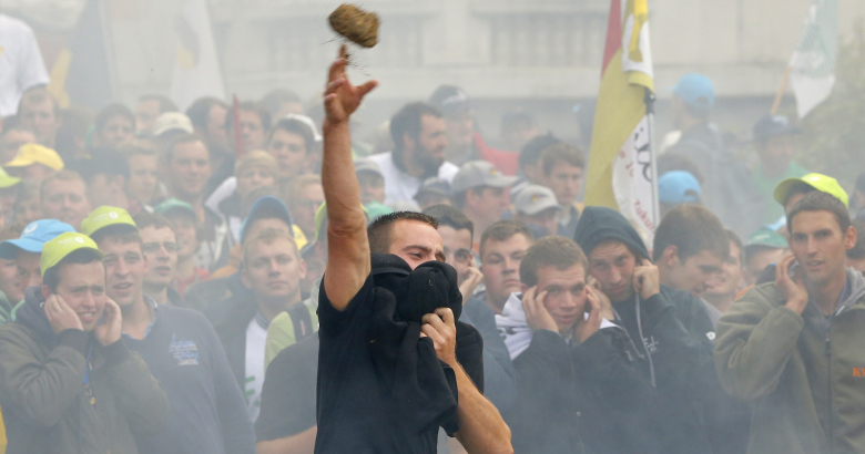 Протестующий бросает в полицейских сеном. Брюссель.
