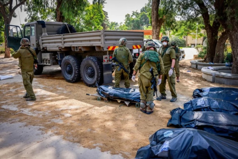 Израильские солдаты выносят тела в кибуце Кфар-Аза, недалеко от границы с сектором Газа