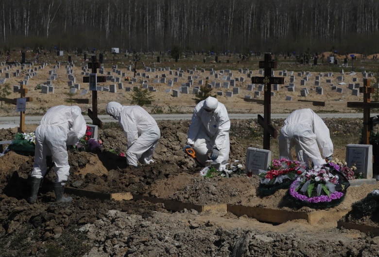 Работники кладбища, одетые в защитное снаряжение, во время похорон жителя, умершего от коронавирусной инфекции COVID-19, Санкт-Петербург. Фото: Anatoly Maltsev / EPA / TASS